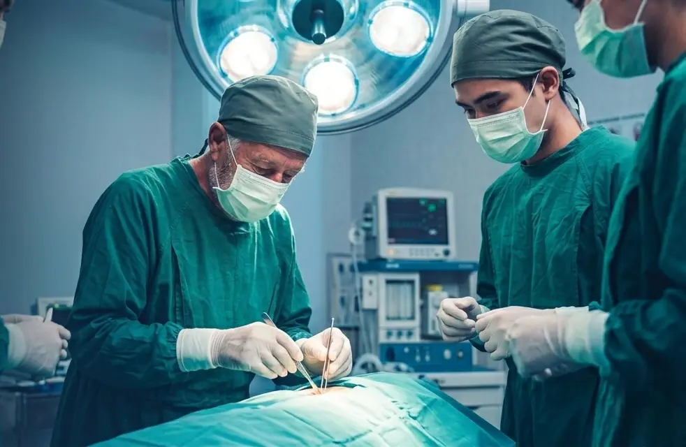 A surgical team performs an operation under bright lights in an operating room.