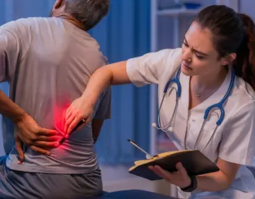 A healthcare professional examines an older man's lower back, which is highlighted with a red glow to indicate pain.